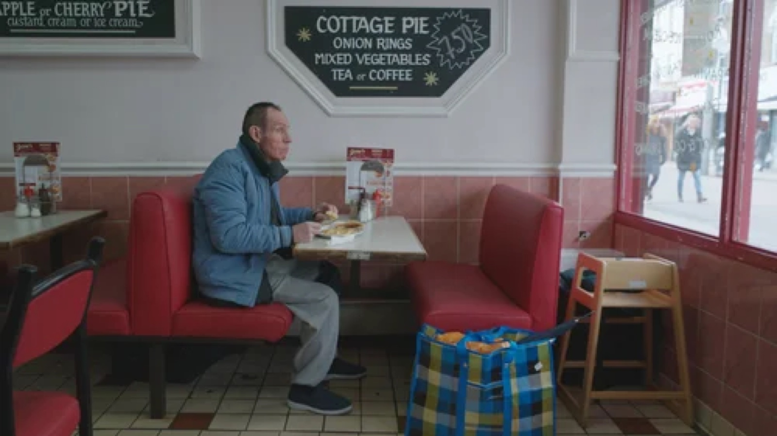 Still from The Legend of King Dick: a man in a blue jacket at his Walthamstow market stall.