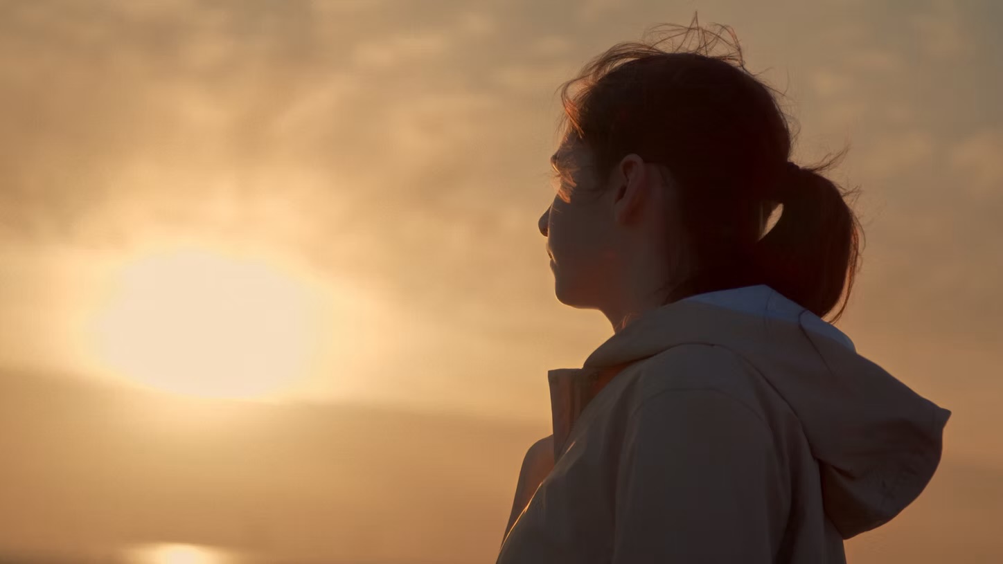 Graded frame from the catalogue: a young woman in profile, lit by a hazy sunset.